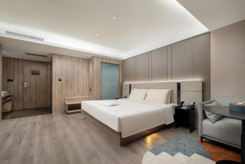 a bedroom with a large white bed and a couch at Atour Hotel Qingdao Olympic Sailing Center May Fourth Square in Qingdao