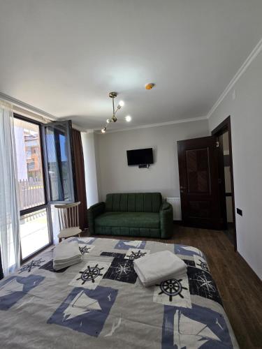 a large bed in a room with a green couch at Aparthotel Alfa in Ureki