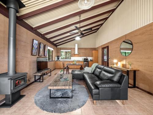 a living room with a leather couch and a stove at Marima Cottages in Pemberton