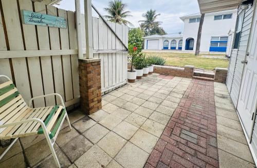 a patio with a bench and a house at Steps to the Sand - Private Beach Access & BBQ Grill in Indialantic