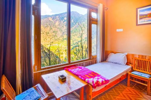 a small room with a bed and a large window at Apple Blush Retreat - Tirthan Valley in Gushaini