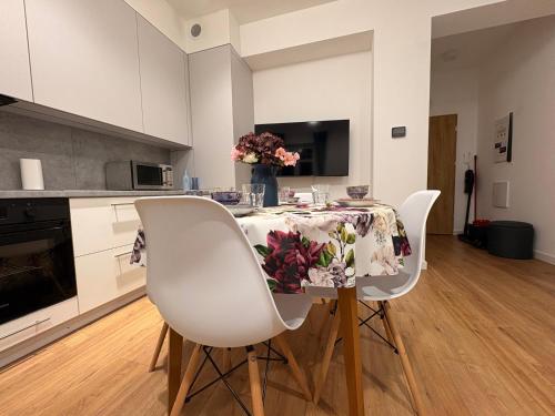 a kitchen with a table and two white chairs at Apartamenty EverySky Kowary, Blue z windą in Kowary