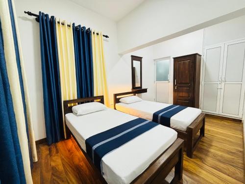two beds in a room with blue and yellow curtains at The Mystic in Talawakele