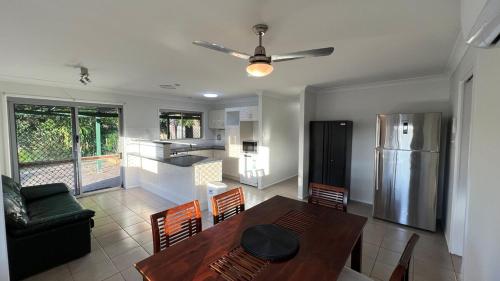 a kitchen with a dining table and a refrigerator at 3 Bed House free parking,Master with AC in Browns Plains