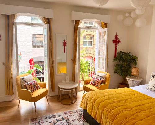 a bedroom with a yellow bed and two chairs at Candy Cafe Apartment in London