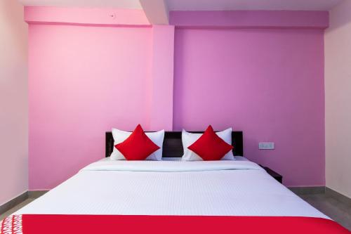 a bedroom with a large bed with red pillows at Hotel O Decision in Akolia