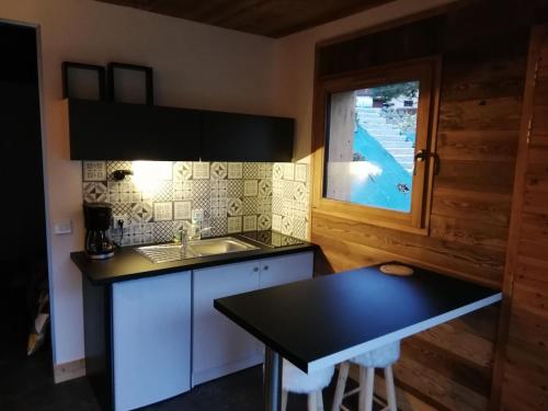 une cuisine avec un évier, une table et une fenêtre dans l'établissement Nature and mountain studio, à La Plagne Tarentaise