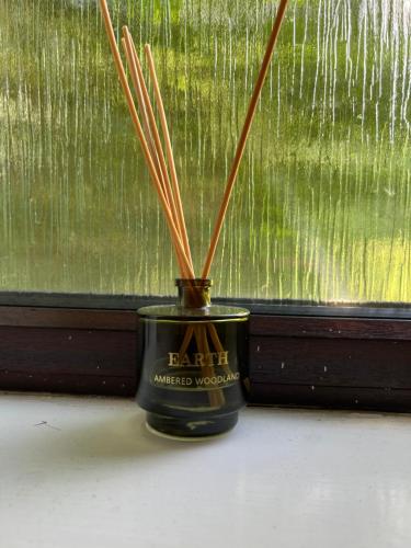 a black jar with sticks in it next to a window at London 2 bed-Apartment BEAUTIFUL in Borehamwood