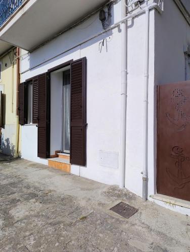 a white building with brown shutters and a window at Al VICO TREDICI in Gaeta