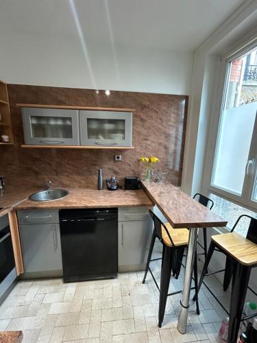 - une cuisine avec un comptoir, un évier et une table dans l'établissement Maison proche Disneyland paris, à Boissy-Saint-Léger