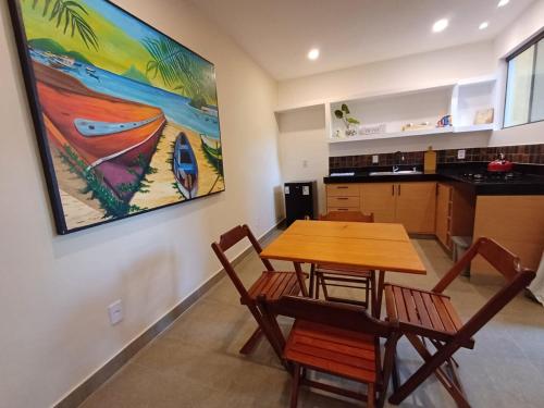 a kitchen with a table and chairs and a painting on the wall at Recanto Tucuns-Guest House in Búzios