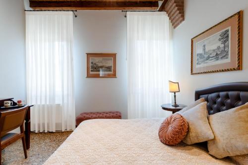 a bedroom with a bed and a desk and curtains at Ca' Santo Spirito B&B in Venice