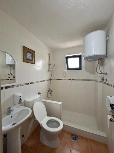 a white bathroom with a toilet and a sink at Guesthouse Liamra in Ulcinj