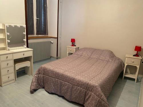 - une chambre avec un lit, deux tables et un miroir dans l'établissement giteMANU, à Arbois