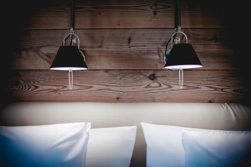 two lights hanging above a bed with two pillows at La Cresta Chalet in Breuil-Cervinia