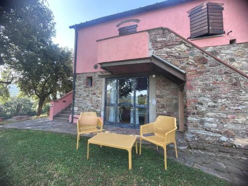 three chairs and a table in front of a building at Agriturismo Colle Donatucci in Castagneto Carducci
