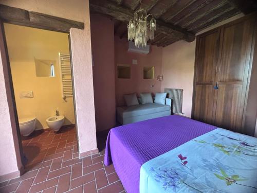 a bedroom with a purple bed and a bathroom at Agriturismo Colle Donatucci in Castagneto Carducci