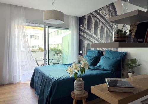 a bedroom with a blue bed with a vase of flowers at Labicum XXII - Modern Luxury Studio near the Colosseum in Rome