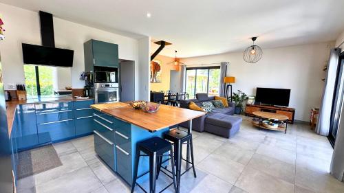 une cuisine avec des armoires bleues et un salon dans l'établissement La Villa Grenadine, à Les Matelles