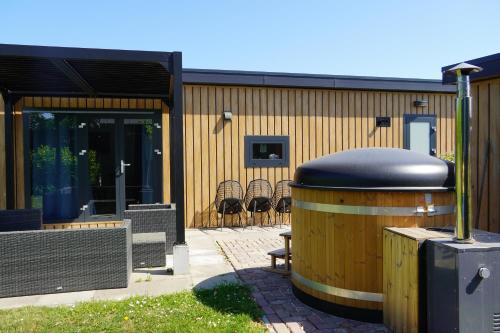 a hot tub sitting next to a building with chairs at Luxe chalet op minicamping in waarde in Waarde