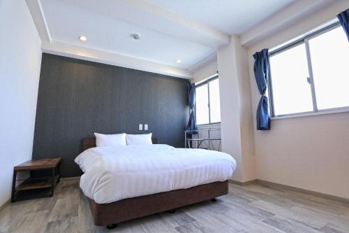 a bedroom with a large bed and two windows at RE Hotel 谷町9丁目 in Osaka