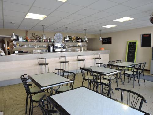 un restaurante con mesas y sillas y un bar en Les Voyageurs, en Vairé