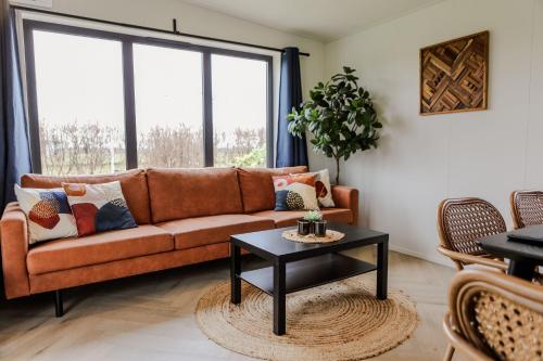 a living room with a couch and a table at Luxe chalet op minicamping in waarde in Waarde