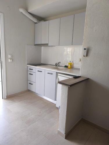 a kitchen with white cabinets and a sink and a counter at Kiparissis Apartments in Kriopigi