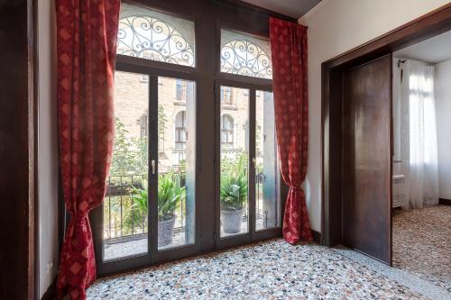a room with large glass doors and red curtains at Ca' Santo Spirito B&B in Venice