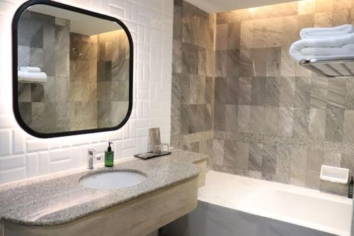 a bathroom with a sink and a mirror at The Quarter Saphankhwai by UHG in Bangkok