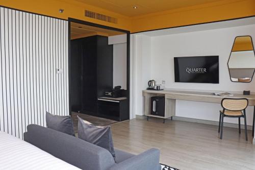 a hotel room with a couch and a desk with a television at The Quarter Saphankhwai by UHG in Bangkok