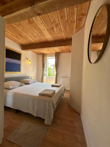 une chambre avec un lit et un miroir au mur dans l'établissement Duplex refait à neuf Village au coeur de la nature, à Roquestéron