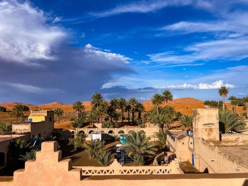 a view of a desert with palm trees and buildings at Hotel Riad Le Petit Prince in Merzouga