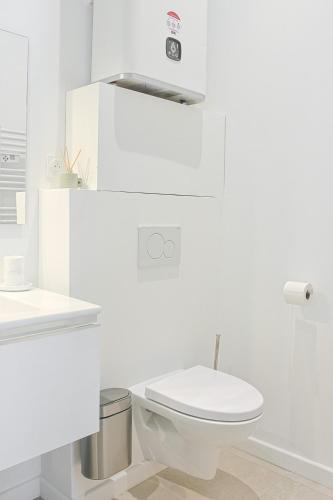 une salle de bain blanche avec des toilettes et un lavabo dans l'établissement Le Refuge des Vignes - Centre Ville - Elégant, à Bordeaux