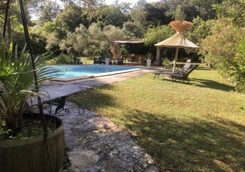 - une piscine dans une cour avec une chaise et un parasol dans l'établissement Mazet des closades, à Saint-Bauzille-de-Montmel