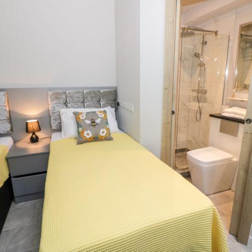 a bedroom with a yellow bed and a shower at Entire cottage close to Coventry City Centre with 4 en suite bedrooms and gated parking in Coventry