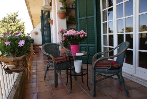 a porch with three chairs and a table with flowers at Giogaia in Modica