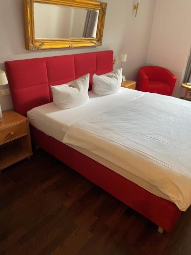 a bed with a red headboard and a red chair at Burg Wegberg Hotel & Eventlocation in Wegberg