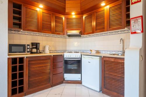 a kitchen with wooden cabinets and a white refrigerator at Bellavista Avenida By BeGuest in Albufeira