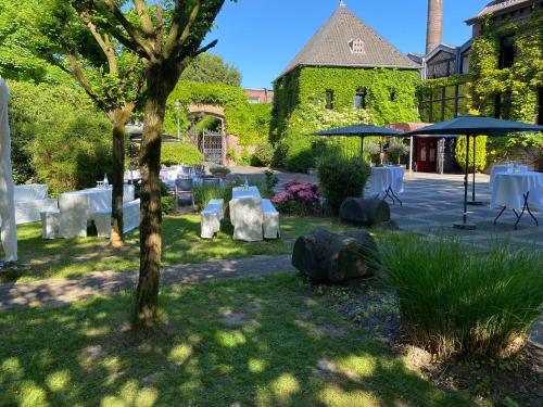 a garden with tables and umbrellas in front of a building at Burg Wegberg Hotel & Eventlocation in Wegberg