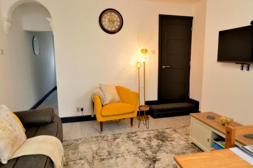 a living room with a couch and a clock on the wall at Grace home by Esongrace stays in Stoke on Trent