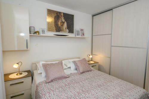 a bedroom with a bed with pink pillows at Val in Kaštela