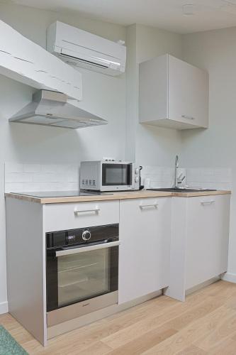 une cuisine avec des armoires blanches et un micro-ondes dans l'établissement Le Patio Secret - Elégance en Centre Ville, à Bordeaux