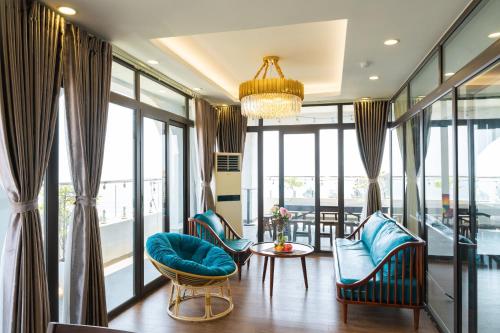 a living room with blue chairs and a chandelier at WILD HORSE Hotel - Khách sạn biển Hải Tiến in Mỹ Ðuc