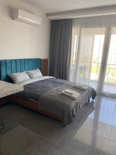 a bedroom with a bed and a large window at Iskele Courtyard Long Beach Apartment in Iskele