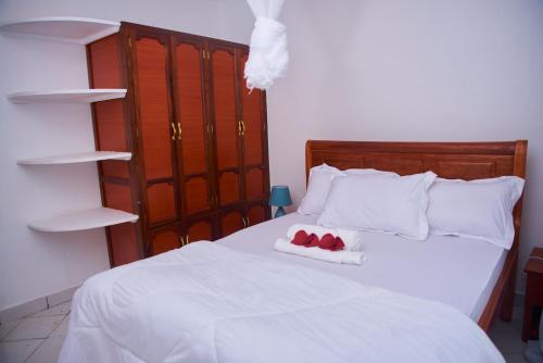 a white bed with two red candles on it at Villa Malkia's in Enaboishu