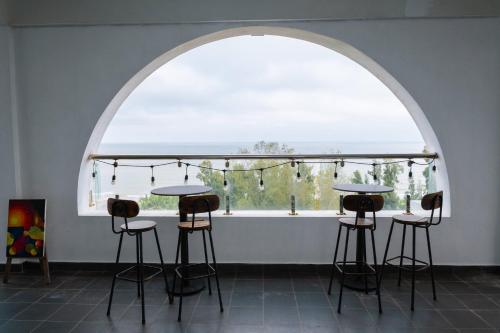 an arched window with three bar stools in a room at WILD HORSE Hotel - Khách sạn biển Hải Tiến in Mỹ Ðuc