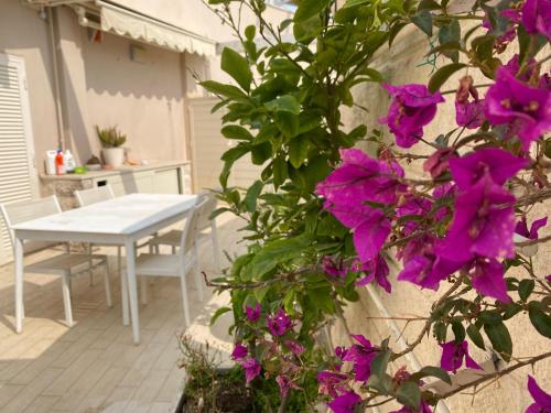 ein weißer Tisch und lila Blumen auf einer Terrasse in der Unterkunft La Terrazza sul Borgo in Fregene