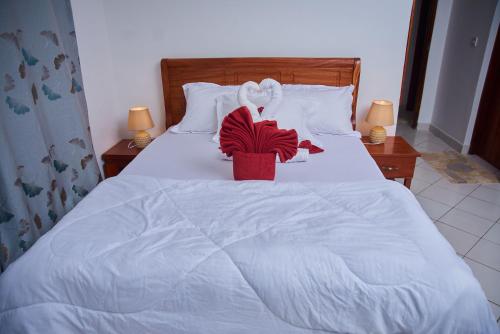 a white bed with a red flower on it at Villa Malkia's in Enaboishu