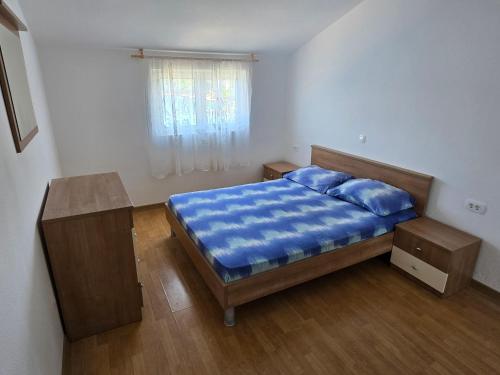 a bedroom with a bed with blue sheets and a window at Apartments Marinko in Janjina